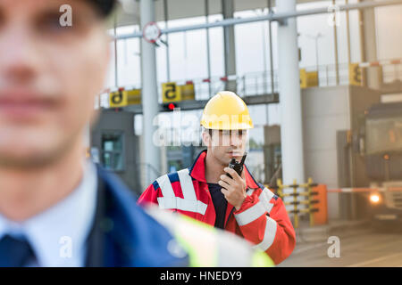 Travailleur à l'aide de talkie-walkie avec collègue en premier plan au Shipyard Banque D'Images