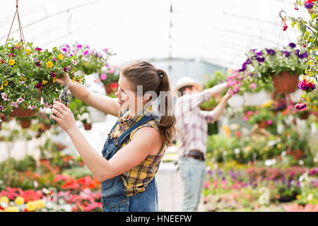 Jardinier plantes femelles de fraisage avec un collègue en arrière-plan à des émissions Banque D'Images