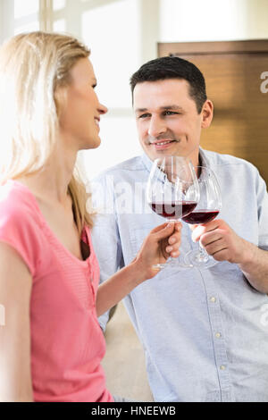 Heureux couple toasting verres à vin rouge dans la cuisine Banque D'Images