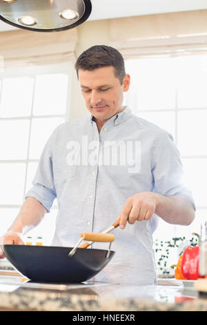 Middle-aged man cooking in kitchen Banque D'Images