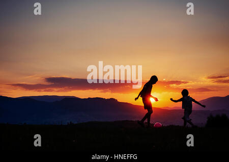 Enfants jouant au coucher du soleil Banque D'Images