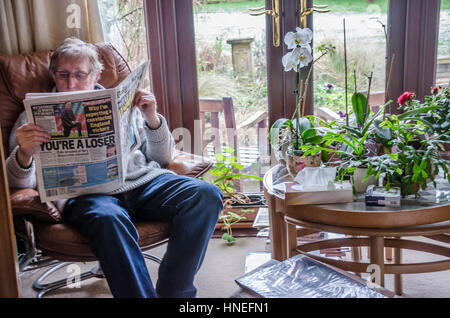 Un homme est assis dans un fauteuil confortable de la lecture du journal Daily Mail. Banque D'Images