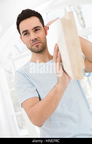 Mid-adult man carrying planche en bois sur l'épaule Banque D'Images