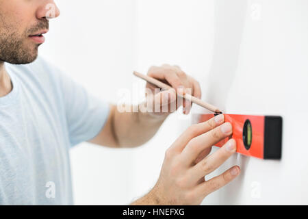 Portrait de l'homme marquant sur le mur avec niveau Banque D'Images