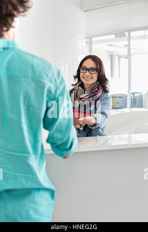 Smiling businesswoman remise au collègue masculin au compteur dans creative office Banque D'Images