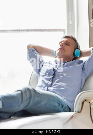 Homme d'âge moyen de détente à écouter de la musique à la maison Banque D'Images