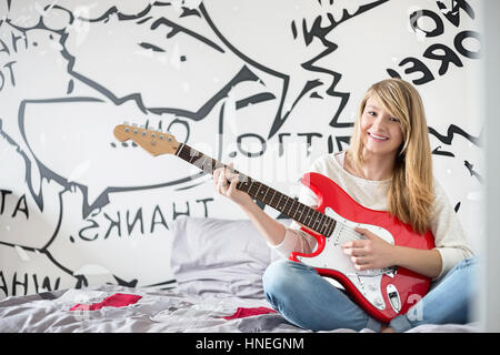 Portrait en pied d'adolescente qui joue de la guitare dans la chambre Banque D'Images