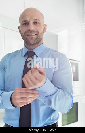 Portrait of Mid adult businessman boutonnant manchon à l'accueil Banque D'Images