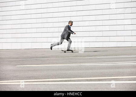 Vue latérale du businessman skateboarding on street Banque D'Images