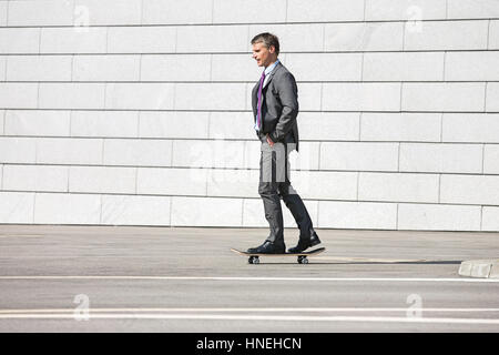 Businessman skateboarding on street Banque D'Images