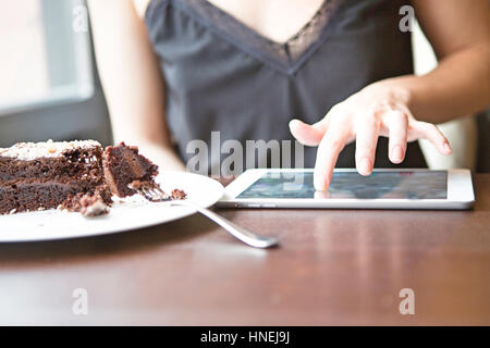 Portrait of woman using tablet PC par pastry in cafe Banque D'Images