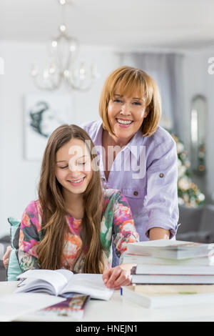 Portrait de mère heureuse d'aider sa fille à faire ses devoirs à la table Banque D'Images