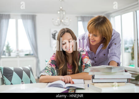 Smiling mother aider sa fille à faire ses devoirs à la table Banque D'Images