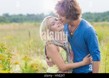 Jeune homme romantique kissing woman in field Banque D'Images