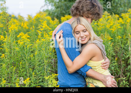 Vue latérale d'affectueux couple hugging in field Banque D'Images