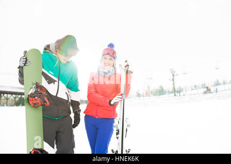 Happy young couple with snowboard et skis dans la neige Banque D'Images
