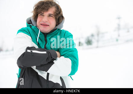 Jeune homme en veste tremblant dans la neige Banque D'Images