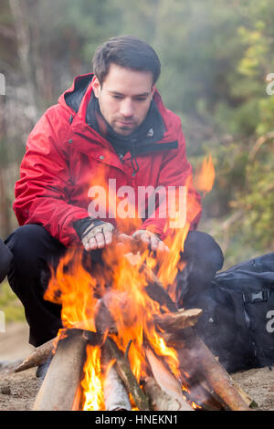 Male hiker réchauffement climatique ses mains au feu de forêt Banque D'Images