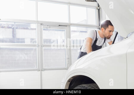 Jeune homme ingénieur d'entretien moteur de voiture réparation en atelier Banque D'Images