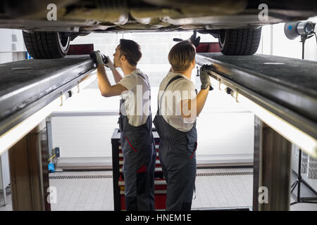 Vue latérale d'ingénieurs de maintenance l'examen de voiture dans l'atelier de réparation Banque D'Images