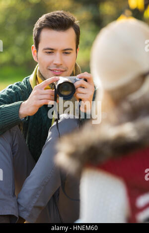 Young man photographing woman in park Banque D'Images