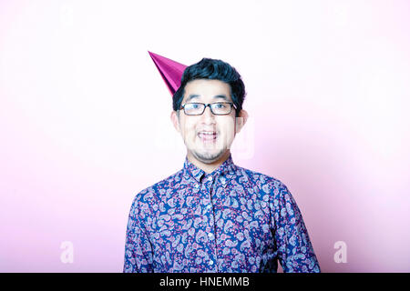 Young Geeky Asian Man wearing party hat Banque D'Images