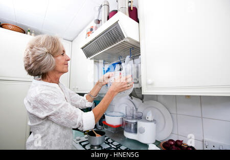 Senior woman hanging passoire dans cuisine domestique Banque D'Images