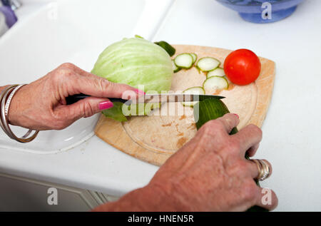 Portrait of senior woman hacher les légumes sur une planche à découper dans la cuisine Banque D'Images