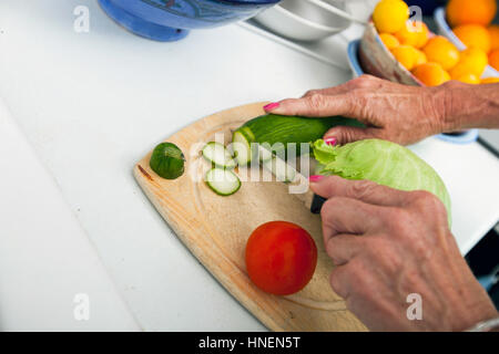 Portrait of senior woman cutting vegetables sur planche à découper dans la cuisine Banque D'Images