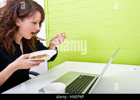 Close up of woman eating at her desk Banque D'Images