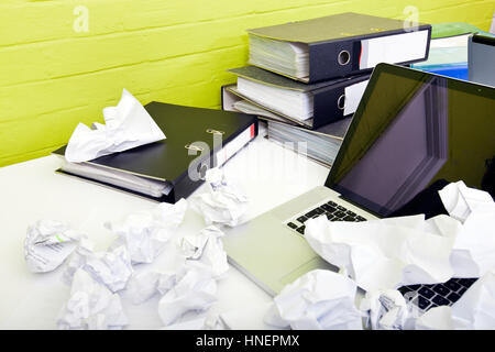 Vue rapprochée de papier froissé sur un ordinateur portable sur un bureau avec chaise vide et dossiers Banque D'Images