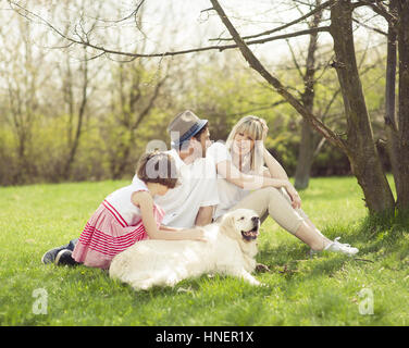 Family sitting in park with dog Banque D'Images