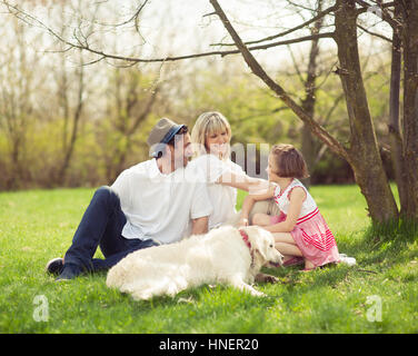 Family sitting in park with dog Banque D'Images