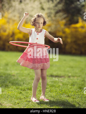 Jeune fille à l'aide de hula hoop dans un parc Banque D'Images