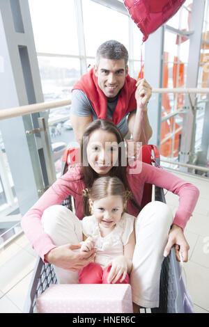 Vue sur l'avant de la mère et de l'jeune fille en chariot avec père poussant Banque D'Images