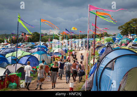 GLASTONBURY, Royaume-Uni - Juin 27, 2014 : les gens marcher dans une aire de camping avec colouful drapeaux à Glastonbury Festival 2014 Banque D'Images