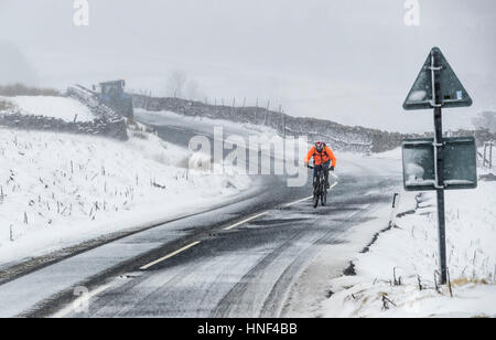 Un cycliste sur le Buttertubs passent dans le Yorkshire Dales comme la neige hits au Royaume-Uni. Banque D'Images