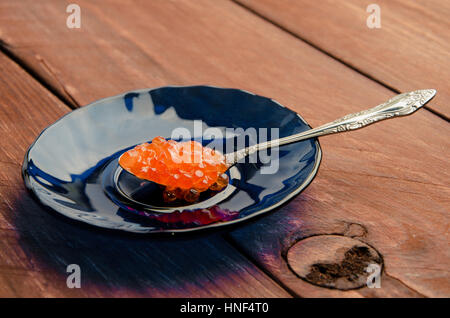 Caviar rouge dans une assiette bleue. plancher bois Banque D'Images