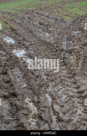 Les traces de pneus de tracteur boueux épais à l'entrée de champ. Métaphore bâton dans la vase, la boue, la texture de surface boueuse, la boue, la boue de l'hiver, les sols marécageux. Banque D'Images