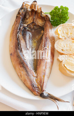 Manx Kippers ou skeddan jiarg harengs fumés naturellement produites dans l'île de Man avec du beurre fondu et des petits pains Banque D'Images