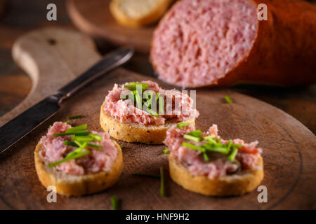 Salé, fumé teewurst une saucisse allemande fait de bacon et de porc, sur des biscottes pain de ciboulette Banque D'Images
