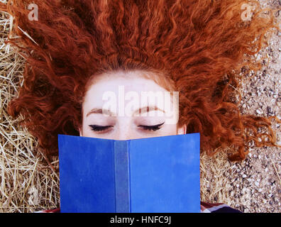 Jeune rousse woman reading a book Banque D'Images