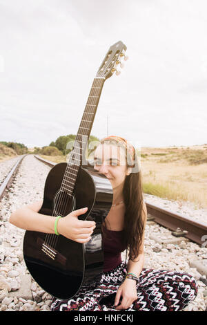 Teen femme dans un chemin de fer avec sa guitare Banque D'Images