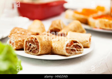 Crêpes roulées avec du poisson du saumon sur une table de fête. Banque D'Images