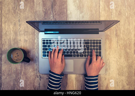 Vue de dessus de tasse à café et female hands typing on laptop clavier de l'ordinateur de bureau en bois de chêne rustique Banque D'Images