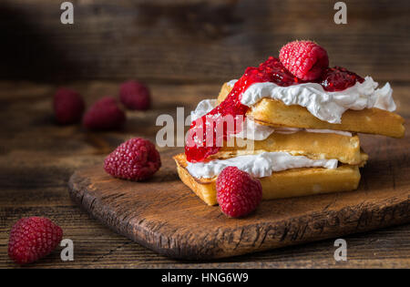 Gaufres Belges avec les framboises et la crème double sur la table rustique. Banque D'Images