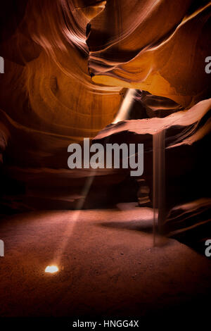 Un faisceau de lumière éclaire l'intérieur de la région de Antelope Canyon, montrant l'effet de l'érosion, murs de grès et de sable qui s'écoule vers le sol, Page, Arizona, USA Banque D'Images