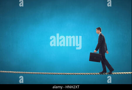 Attention businessman walking sur la corde dans les mains tendues Banque D'Images