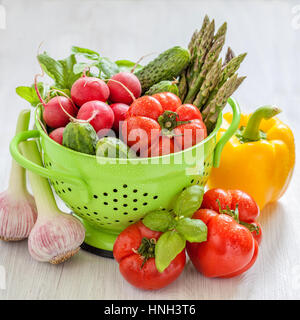 Des légumes frais dans une passoire verte avec de l'eau gouttes Banque D'Images