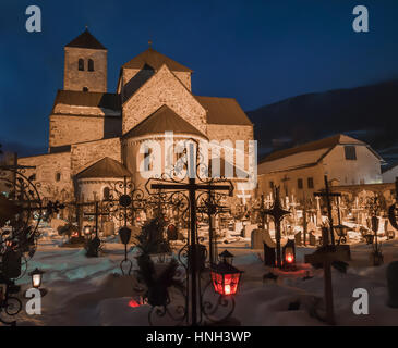 Cimetière de nuit, tout près de la croix, l'église en arrière-plan, il devient matin, neige au sol, des tombes couvertes de neige Banque D'Images